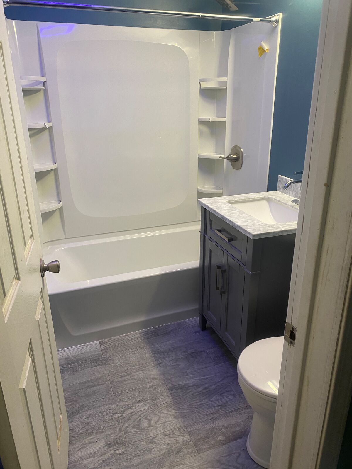 Bathroom with tub surround, gray vanity and plank-look floor