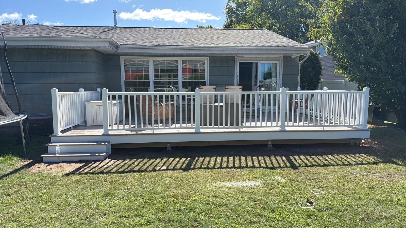 Low deck with white railings across the back of a ranch home