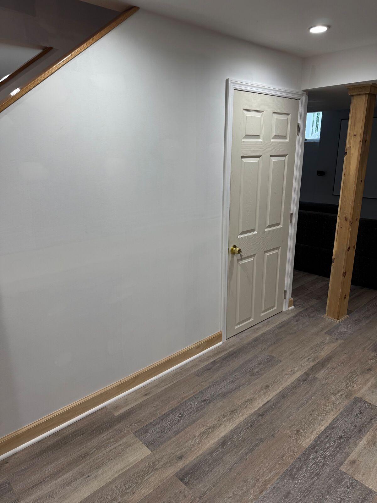 Basement hallway with trimmed door and plank flooring